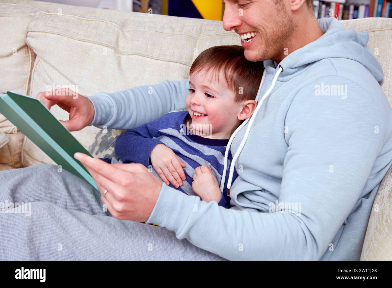 Man and child reading together on a couch Stock Photo