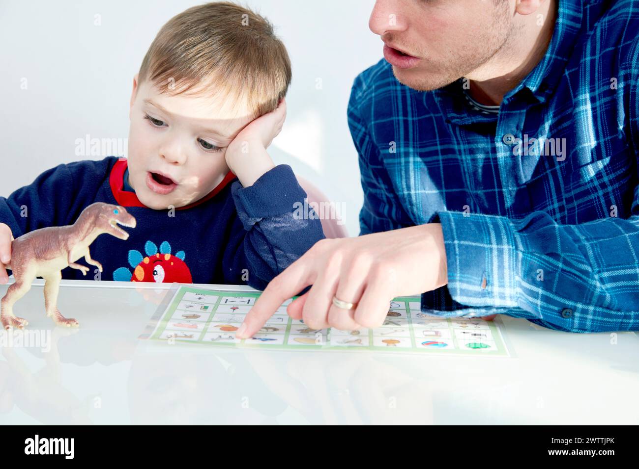 Adult and child engaged in educational play with book and toy Stock Photo