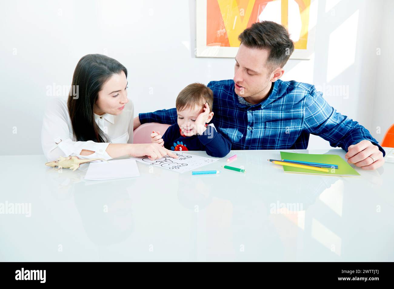 Family coloring together at a white table Stock Photo