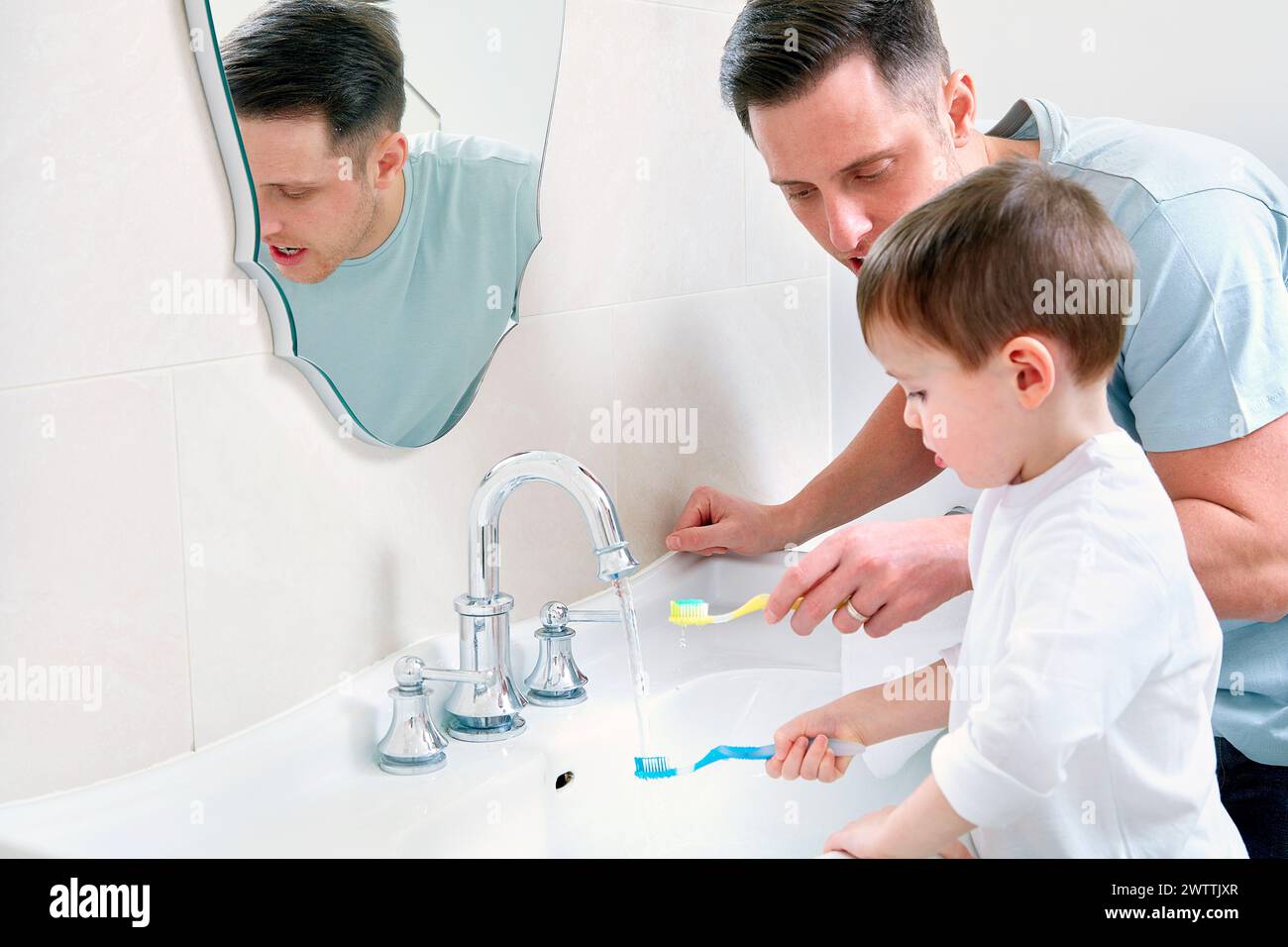 Man and child brushing teeth in bathroom Stock Photo