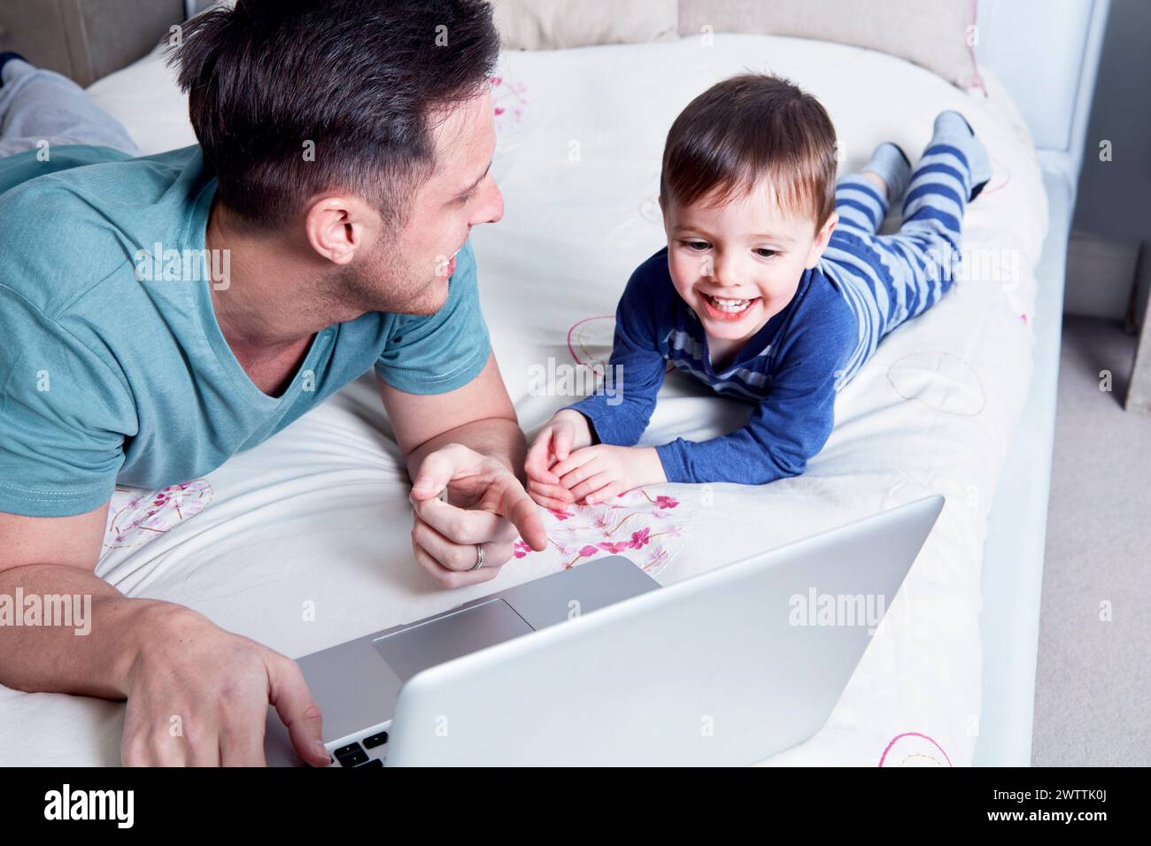 Father and son using laptop on bed Stock Photo