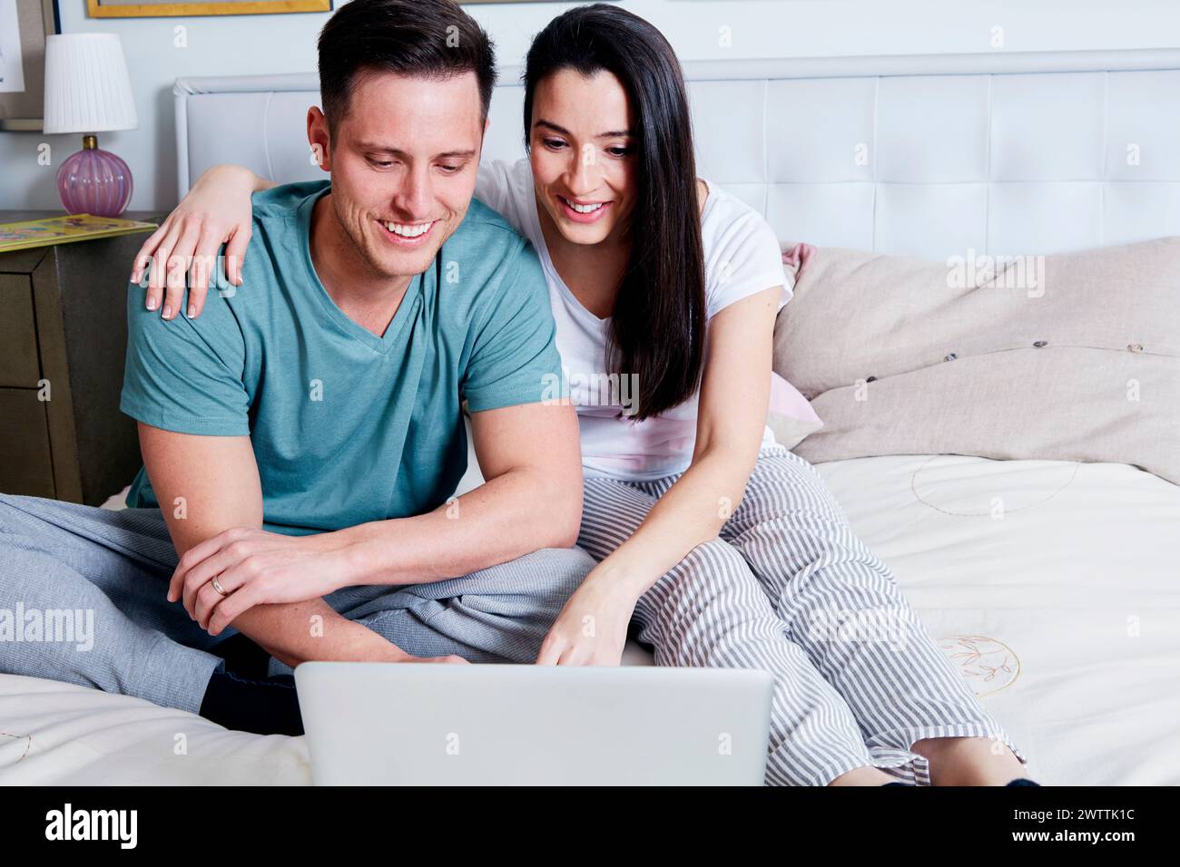 Couple using a laptop on a bed. Stock Photo