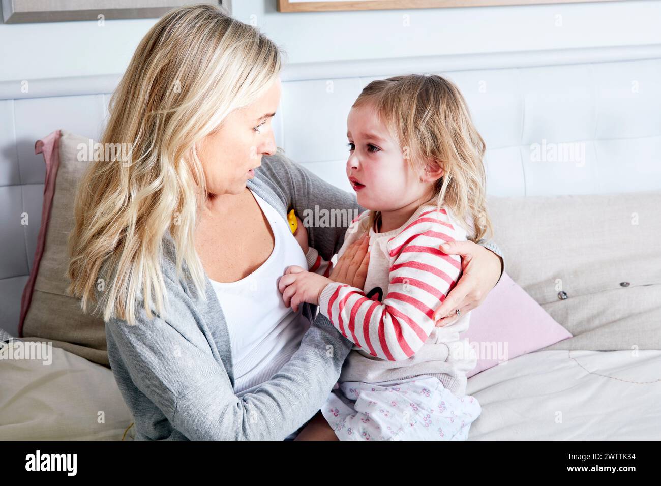 Grandmother comforting crying child on a couch Stock Photo
