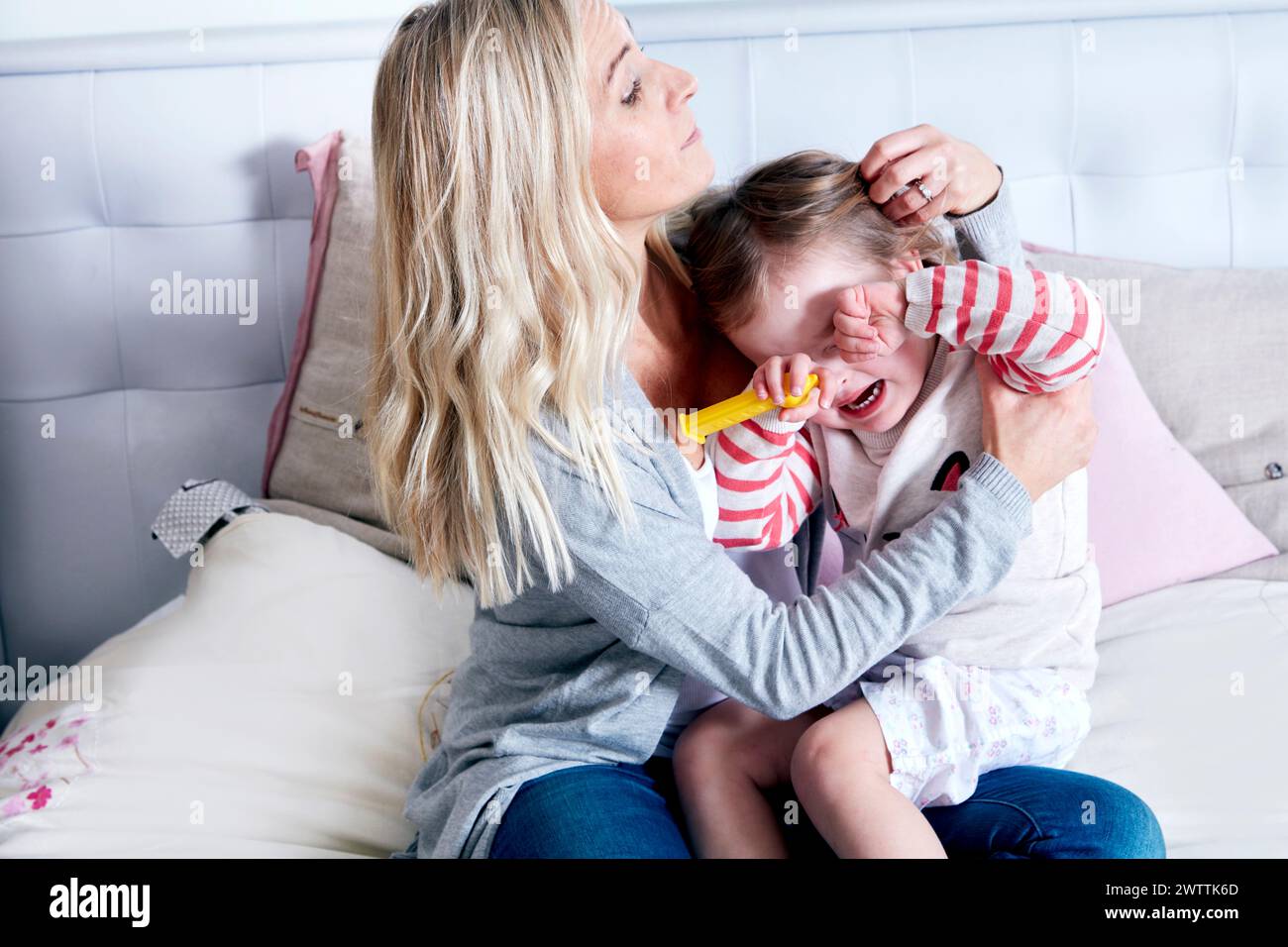 Mother comforting crying child on bed Stock Photo