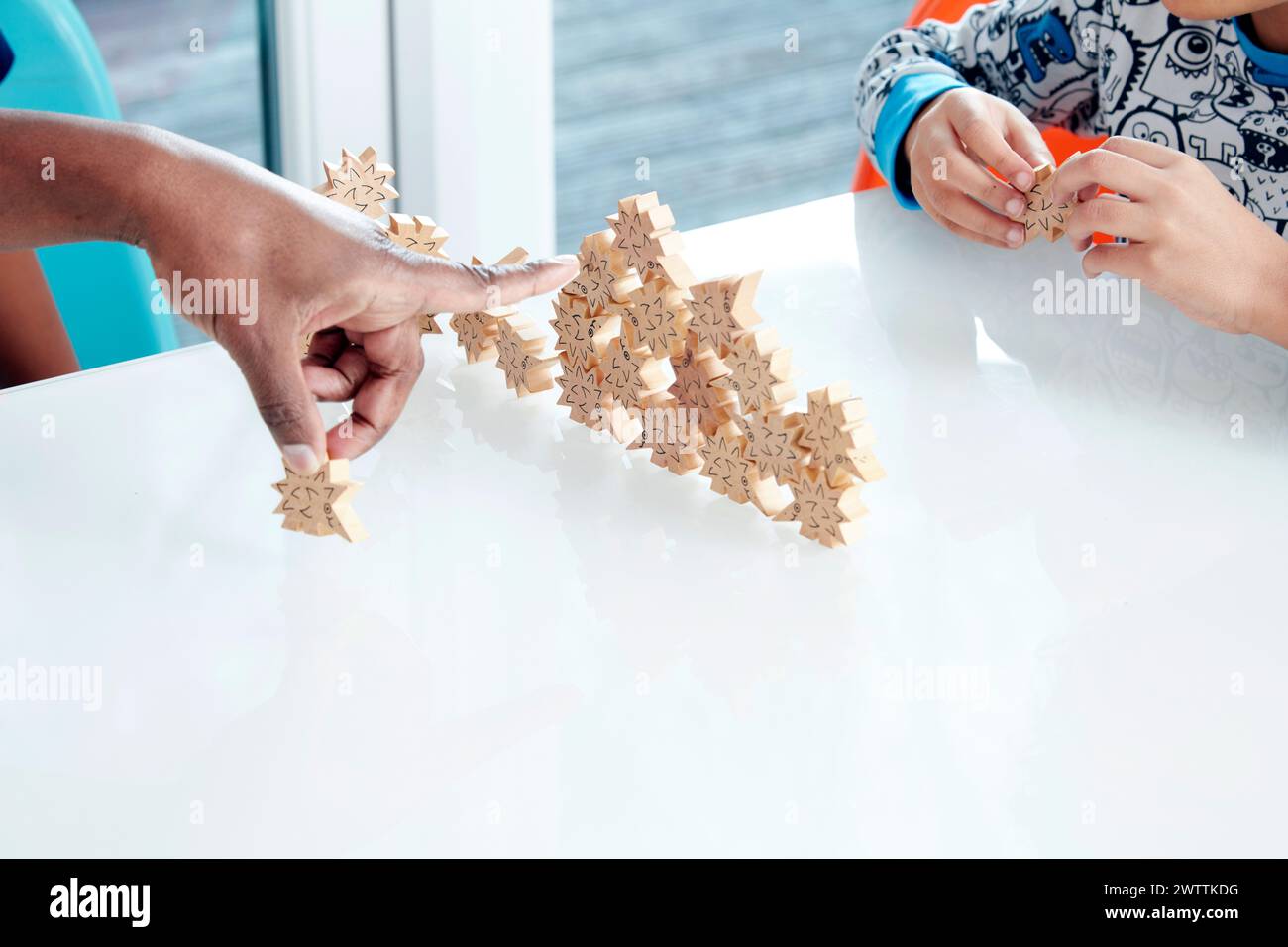 Two individuals playing with wooden star puzzles Stock Photo