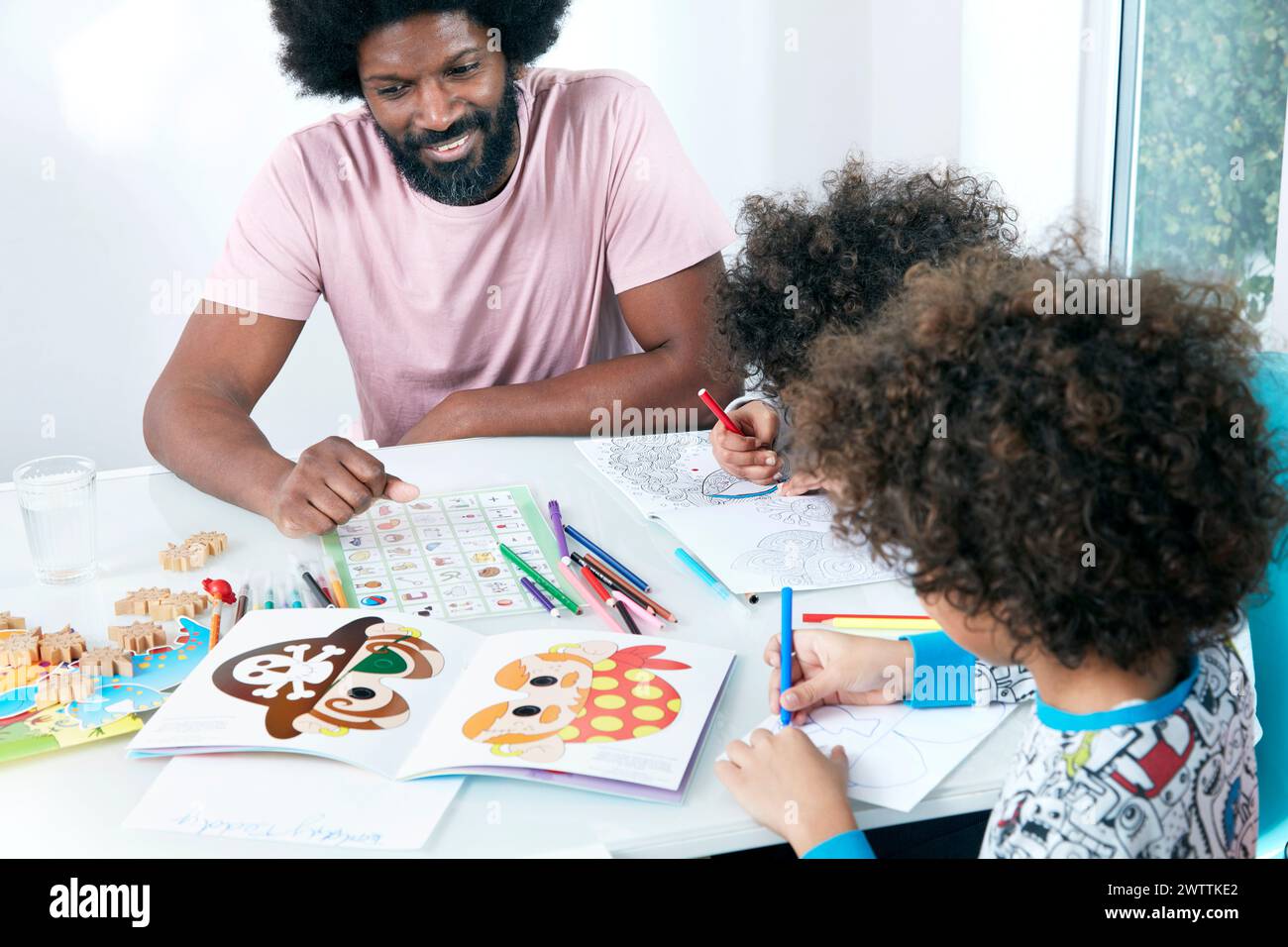 Adult and children engaged in coloring activities Stock Photo