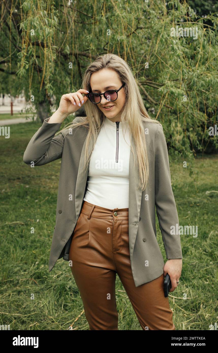 A woman wearing brown pants and a blazer. She stands confidently ...