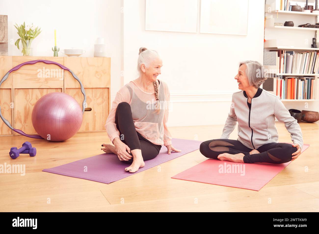 Two women smiling and sitting on yoga mats Stock Photo