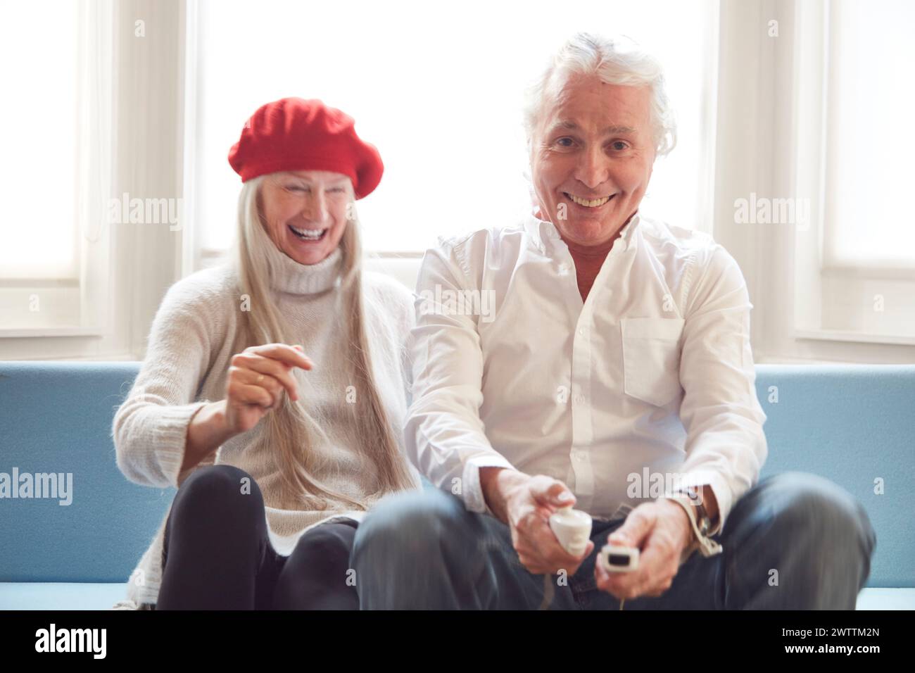 Smiling couple playing video games on a couch Stock Photo