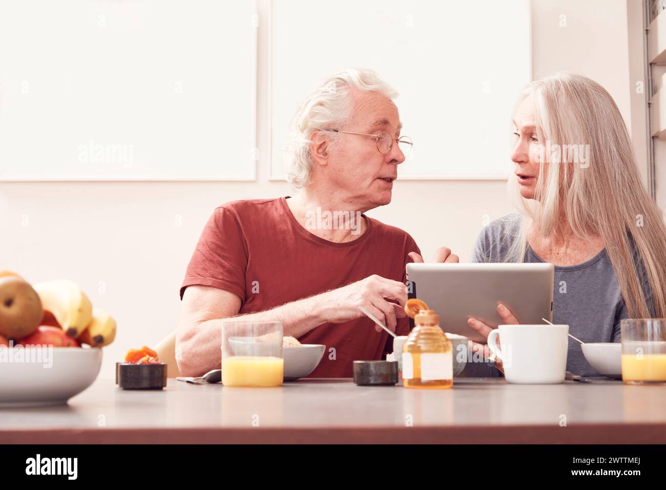 Elderly couple using a tablet at a breakfast table Stock Photo