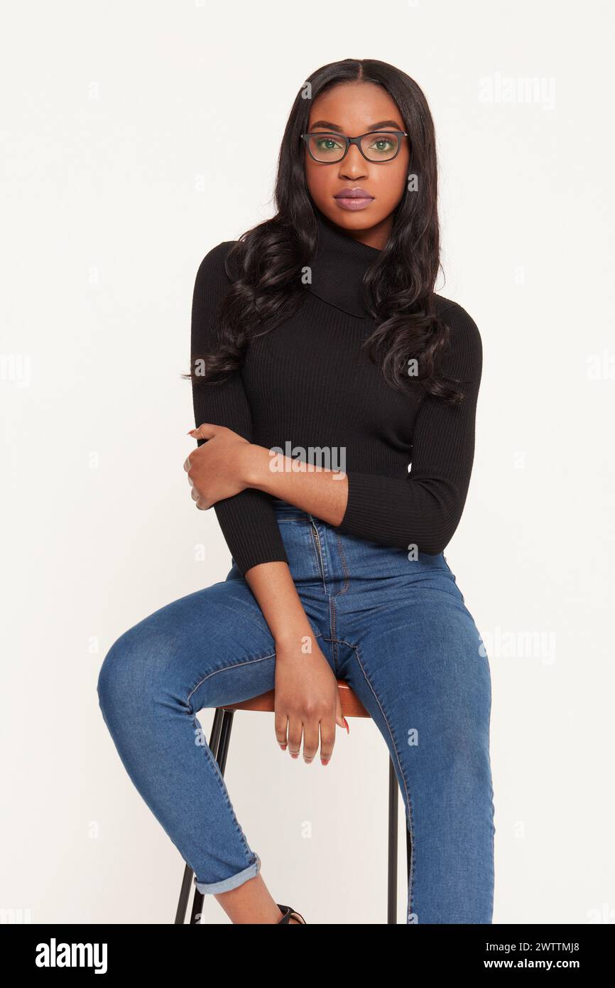 Woman sitting on stool in jeans and black top Stock Photo