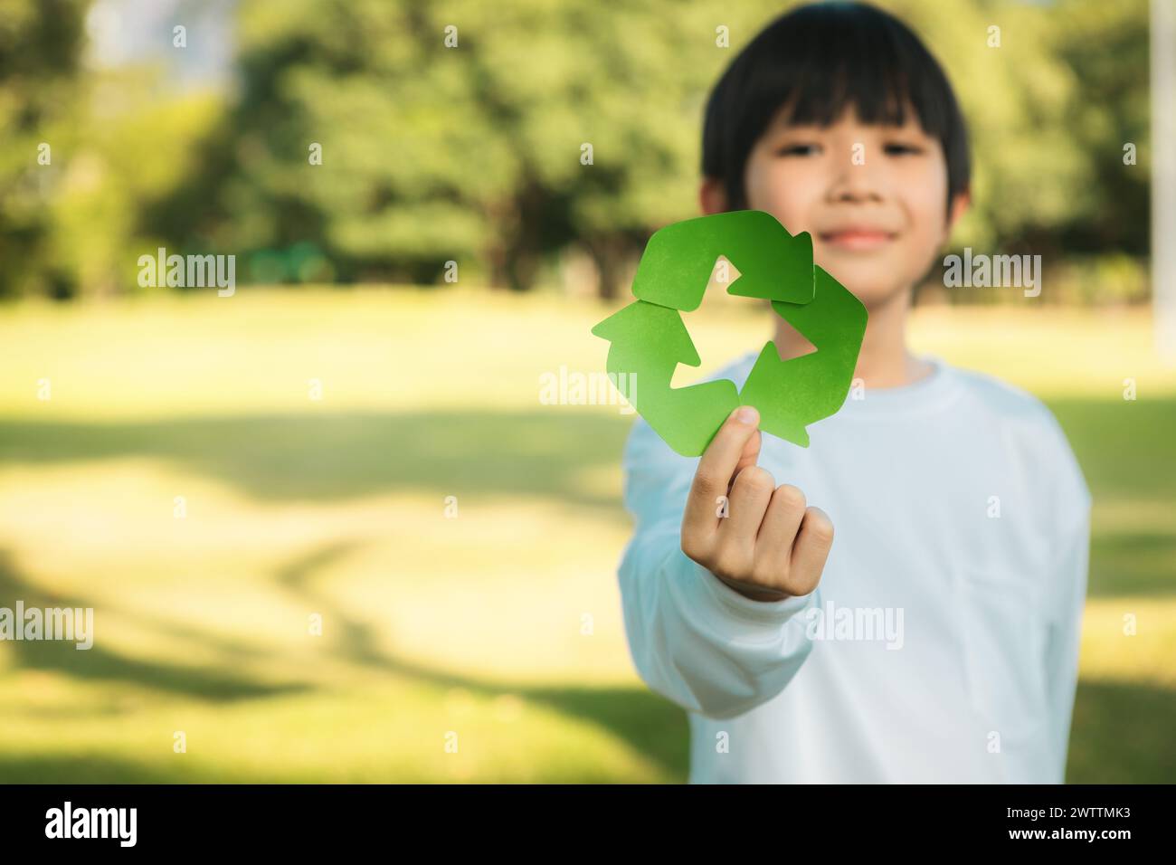 Cheerful young asian boy holding recycle symbol on daylight natural ...