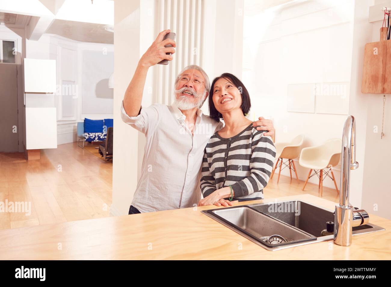Elderly couple taking a selfie in kitchen Stock Photo