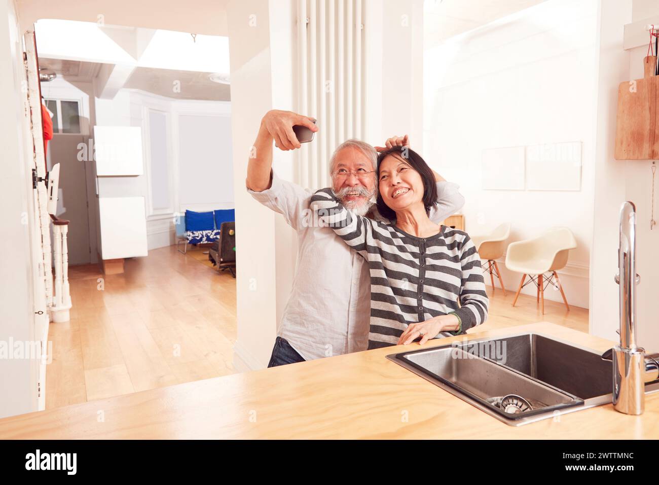 Elderly couple taking a selfie in kitchen Stock Photo