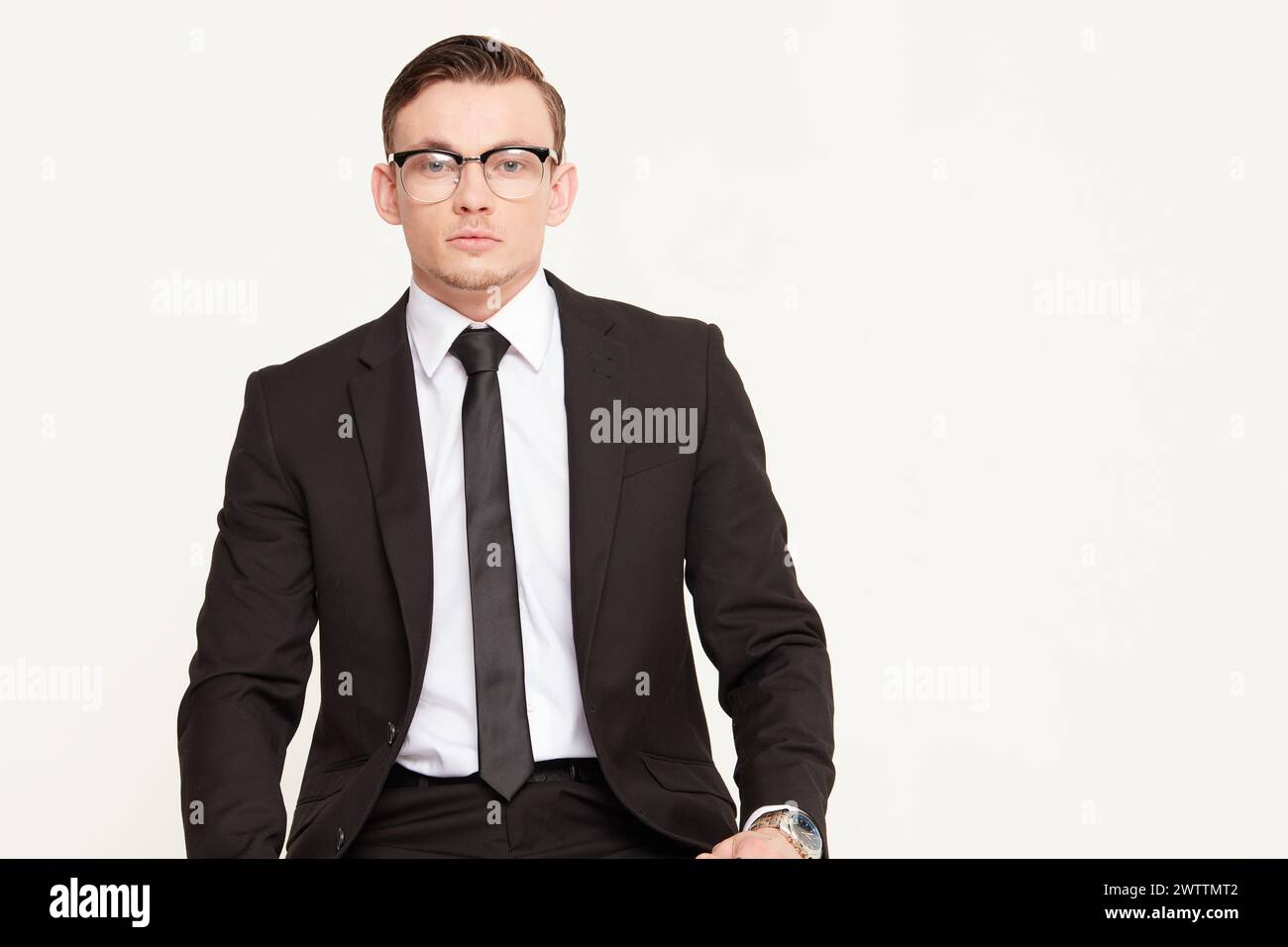 Man in black suit and glasses posing professionally Stock Photo