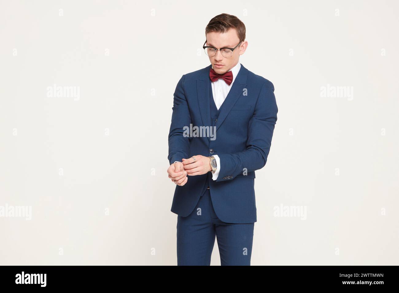 Man in blue suit and red bow tie looking at his watch Stock Photo - Alamy