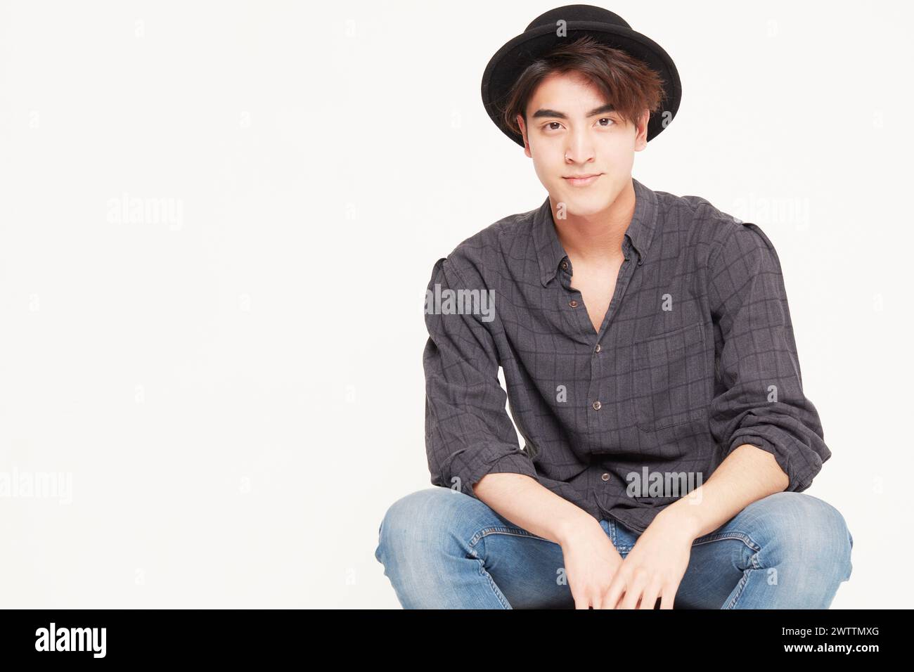 Young man wearing a hat sitting casually Stock Photo