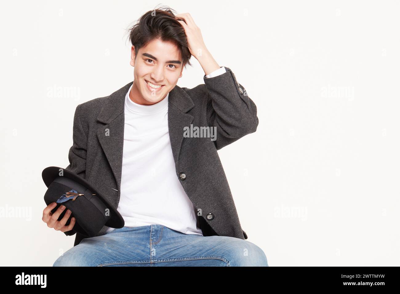 Smiling young man holding a hat Stock Photo