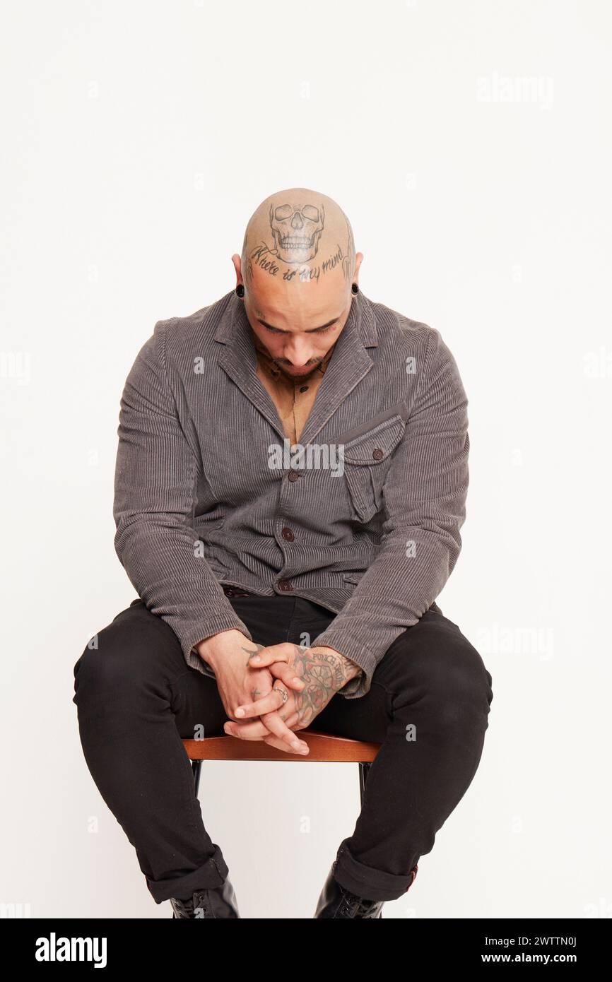 Man with tattoos sitting on a chair Stock Photo