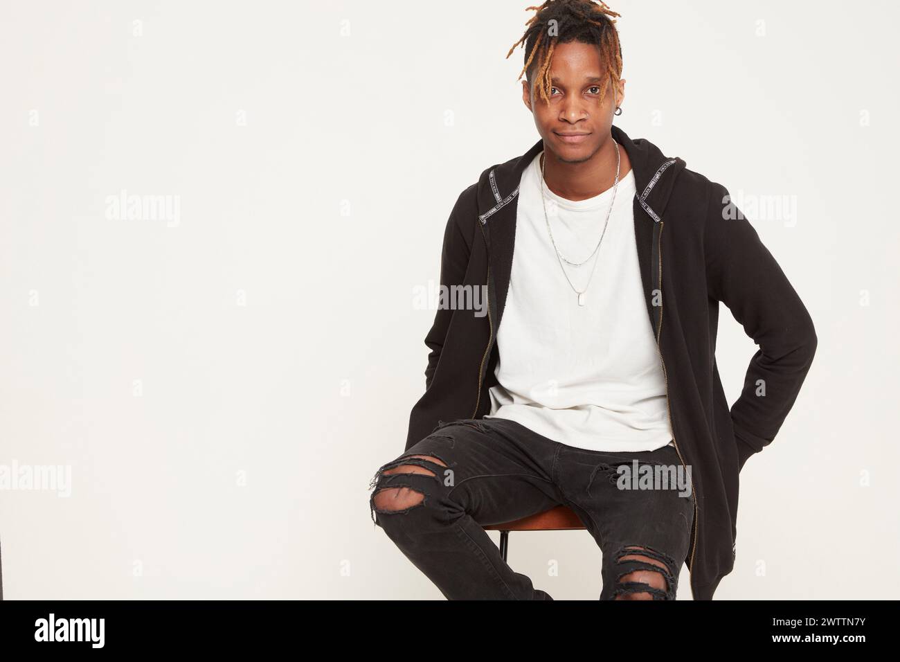 Young person sitting confidently in a studio setting Stock Photo