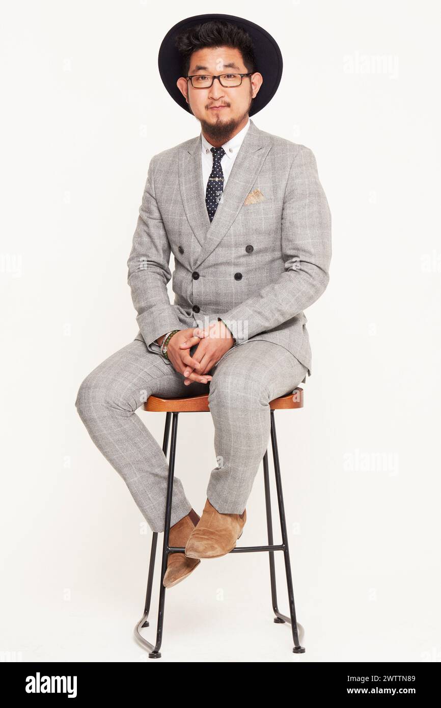 Man in a gray suit sitting on a stool Stock Photo