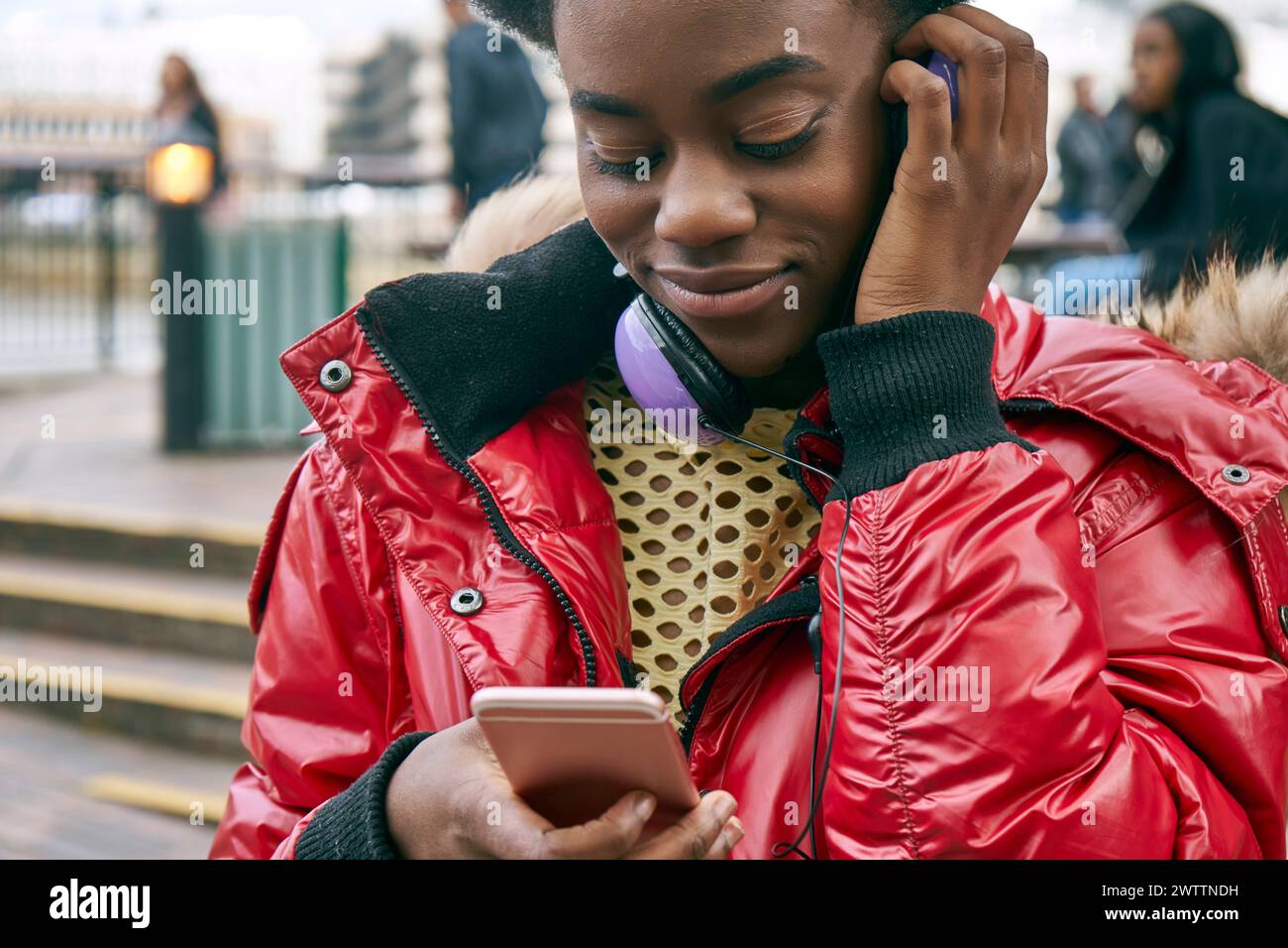 Woman using phone with headphones around neck Stock Photo