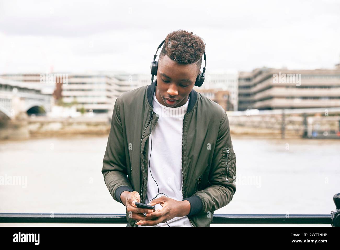Man with headphones using smartphone near a river Stock Photo