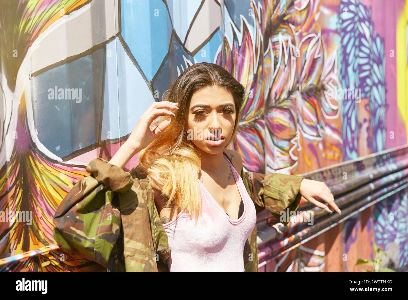 Woman posing in front of colorful graffiti wall Stock Photo