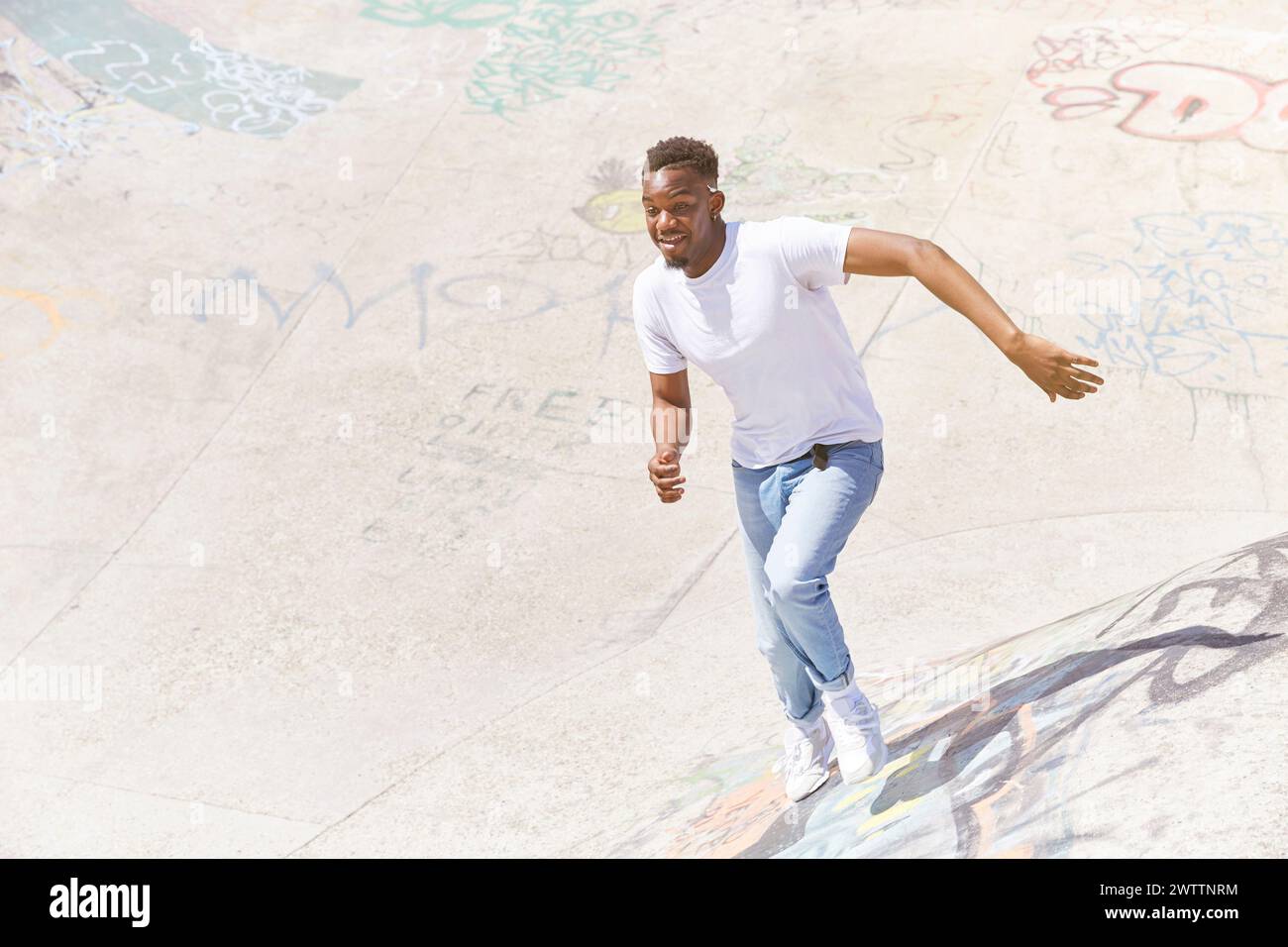 Man skateboarding at a graffiti-covered skatepark. Stock Photo