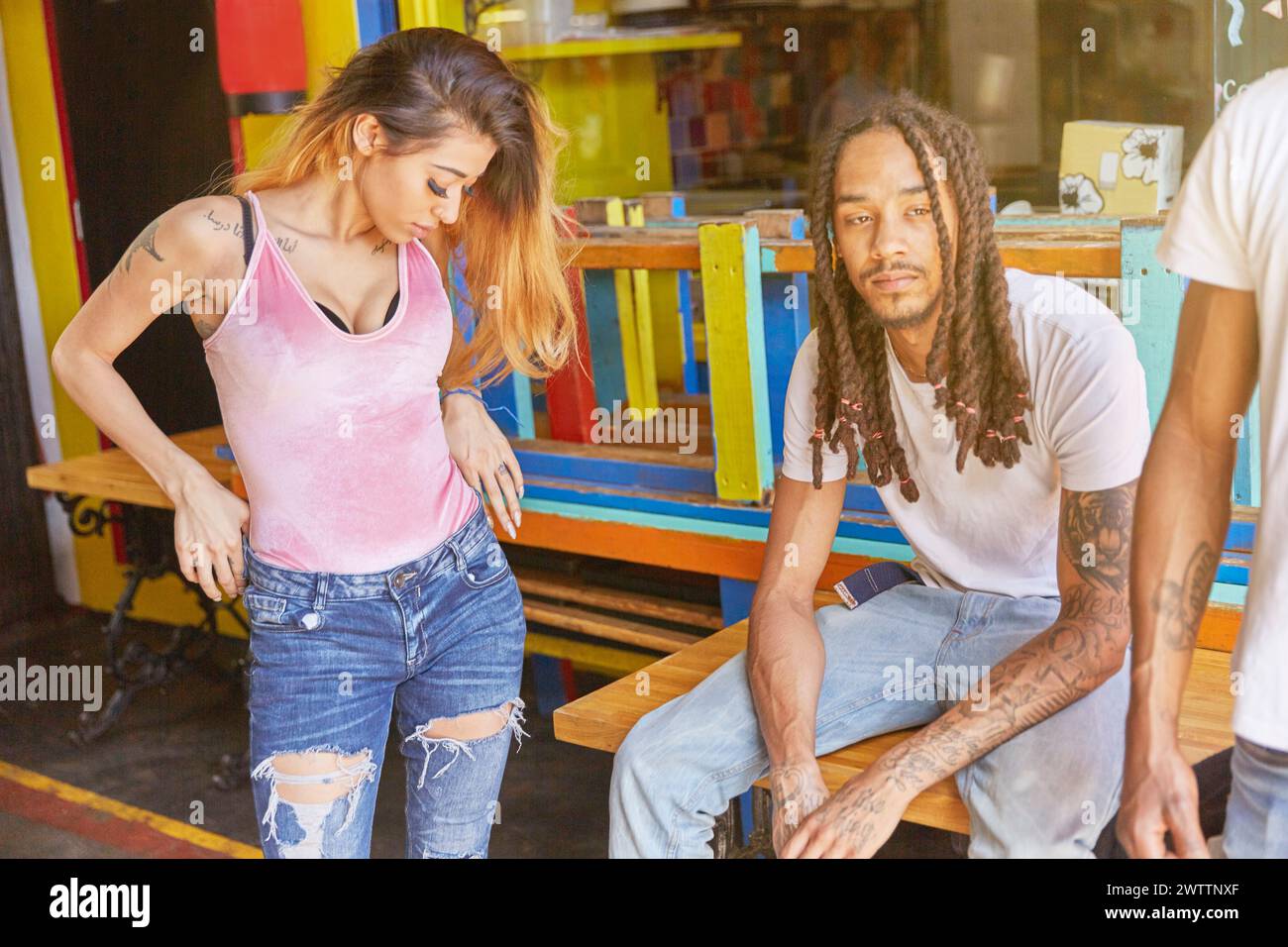 Two people in casual attire sitting outside a colorful establishment Stock Photo
