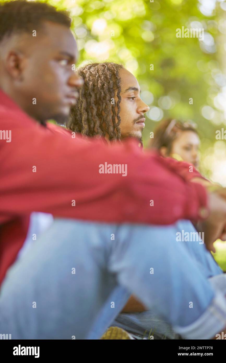 Three people sitting outdoors in a park. Stock Photo