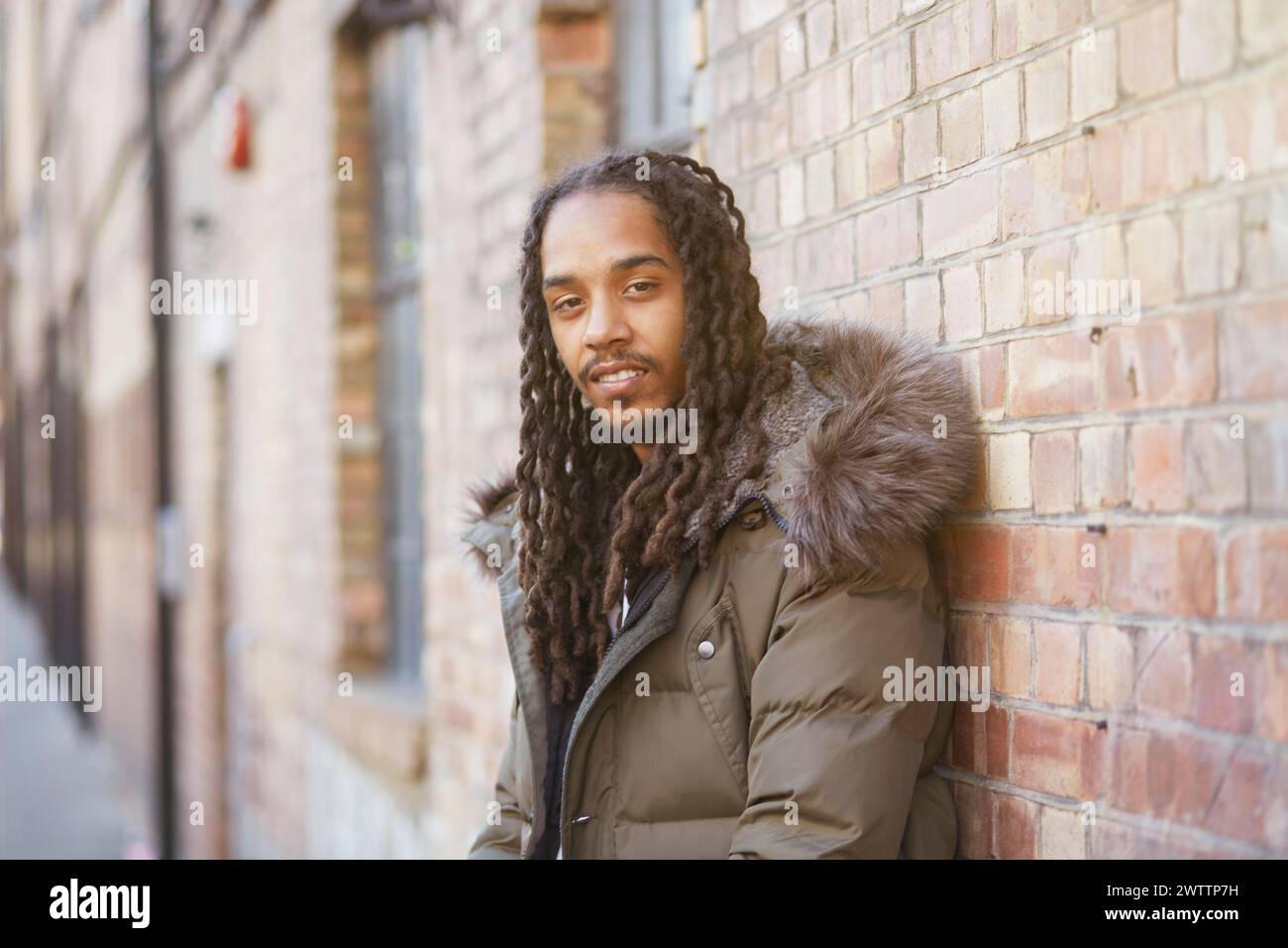 Man leaning against a brick wall Stock Photo