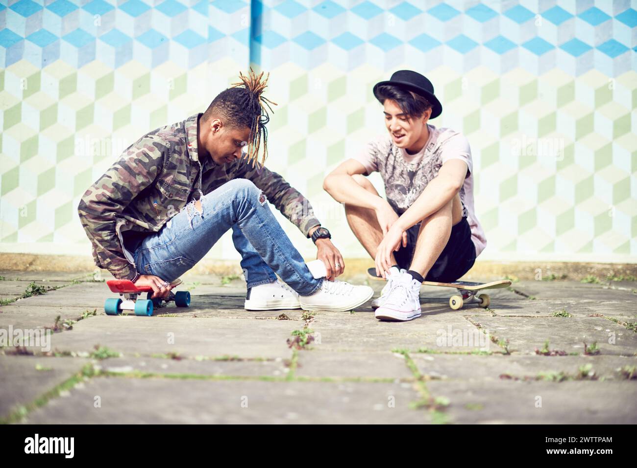 Two individuals sitting and interacting with skateboards Stock Photo