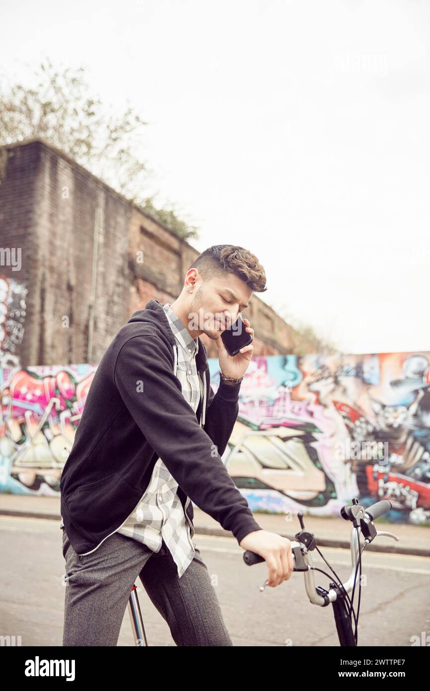 Man talking on the phone while holding a bike Stock Photo