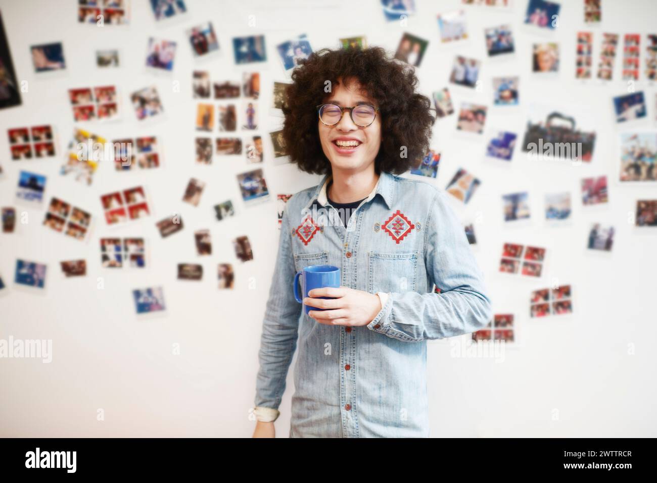 Person with curly hair holding a blue mug Stock Photo