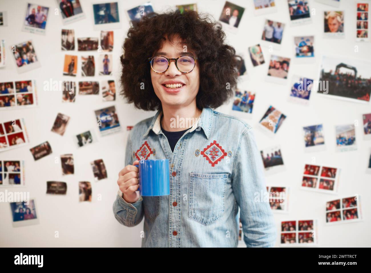 Man with curly hair holding a blue mug Stock Photo
