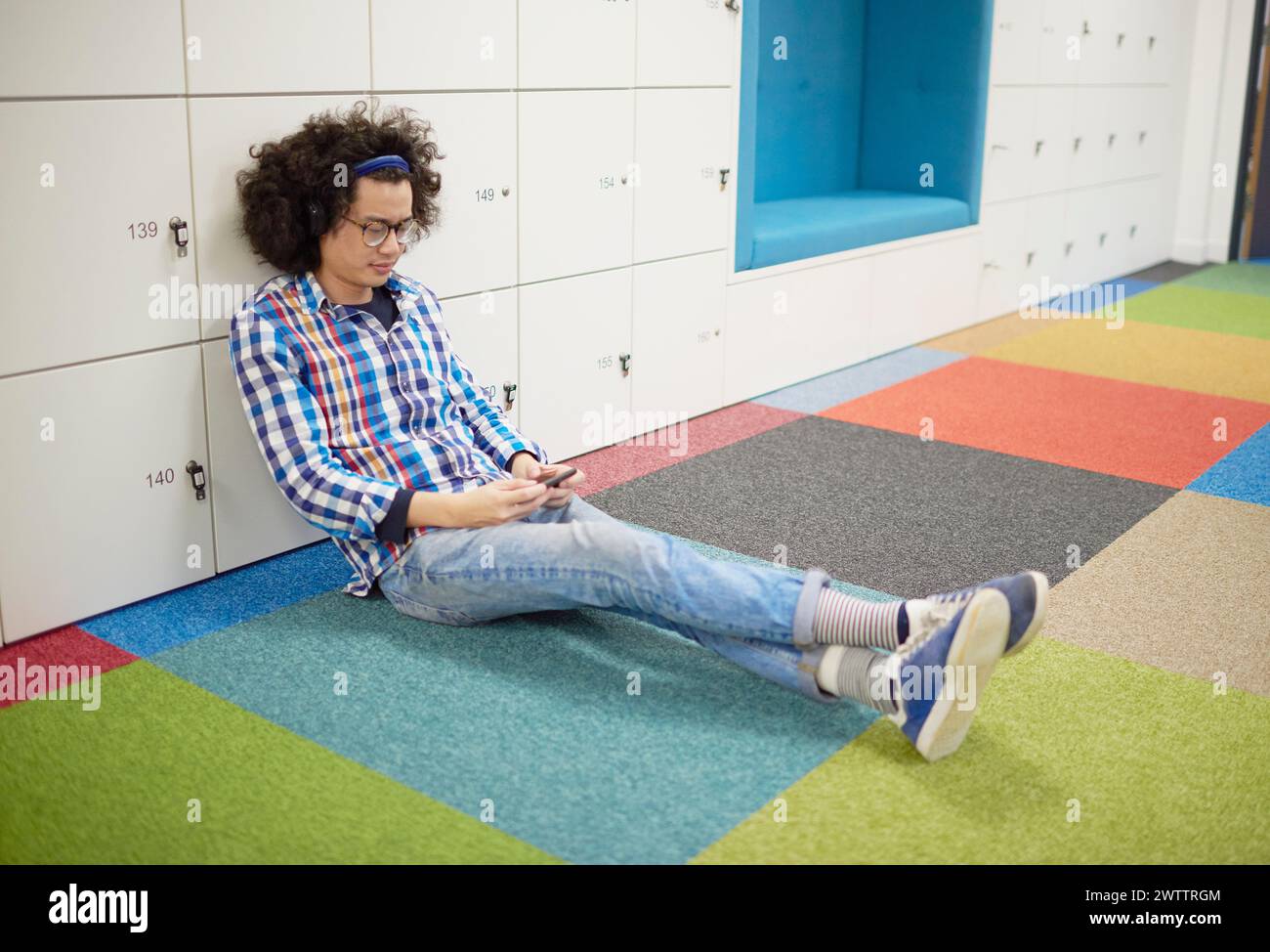 Man sitting on a colorful floor using a smartphone. Stock Photo