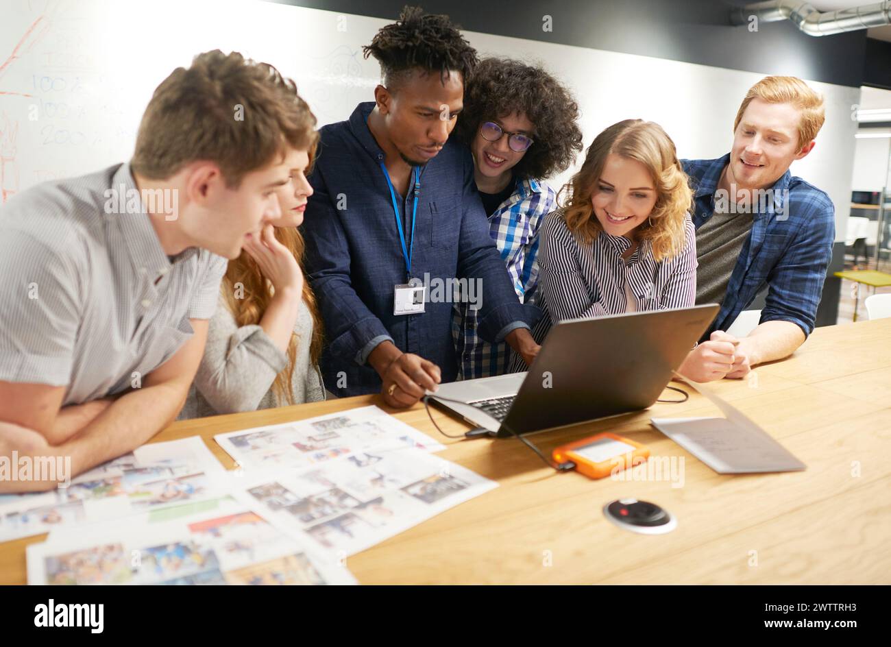 Team collaborating over a laptop in an office Stock Photo