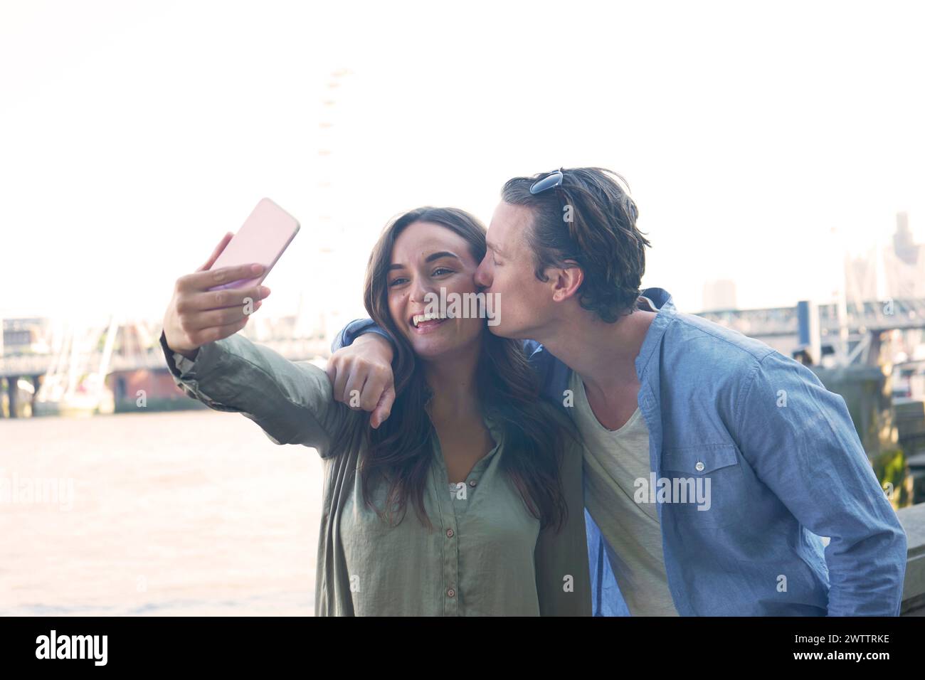 Couple taking a selfie with a city river backdrop Stock Photo