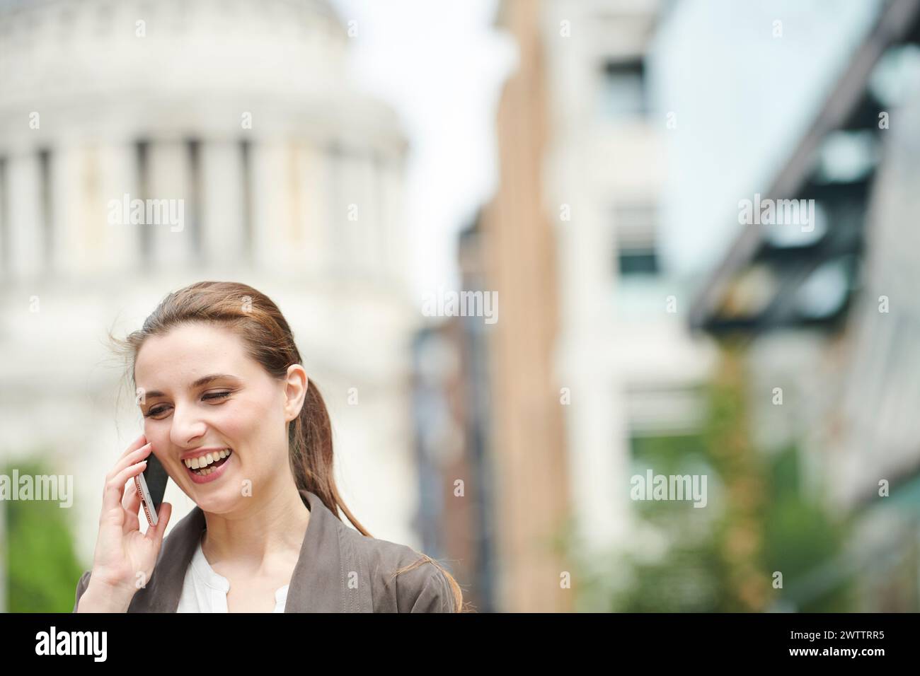 Smiling woman talking on the phone in urban setting Stock Photo