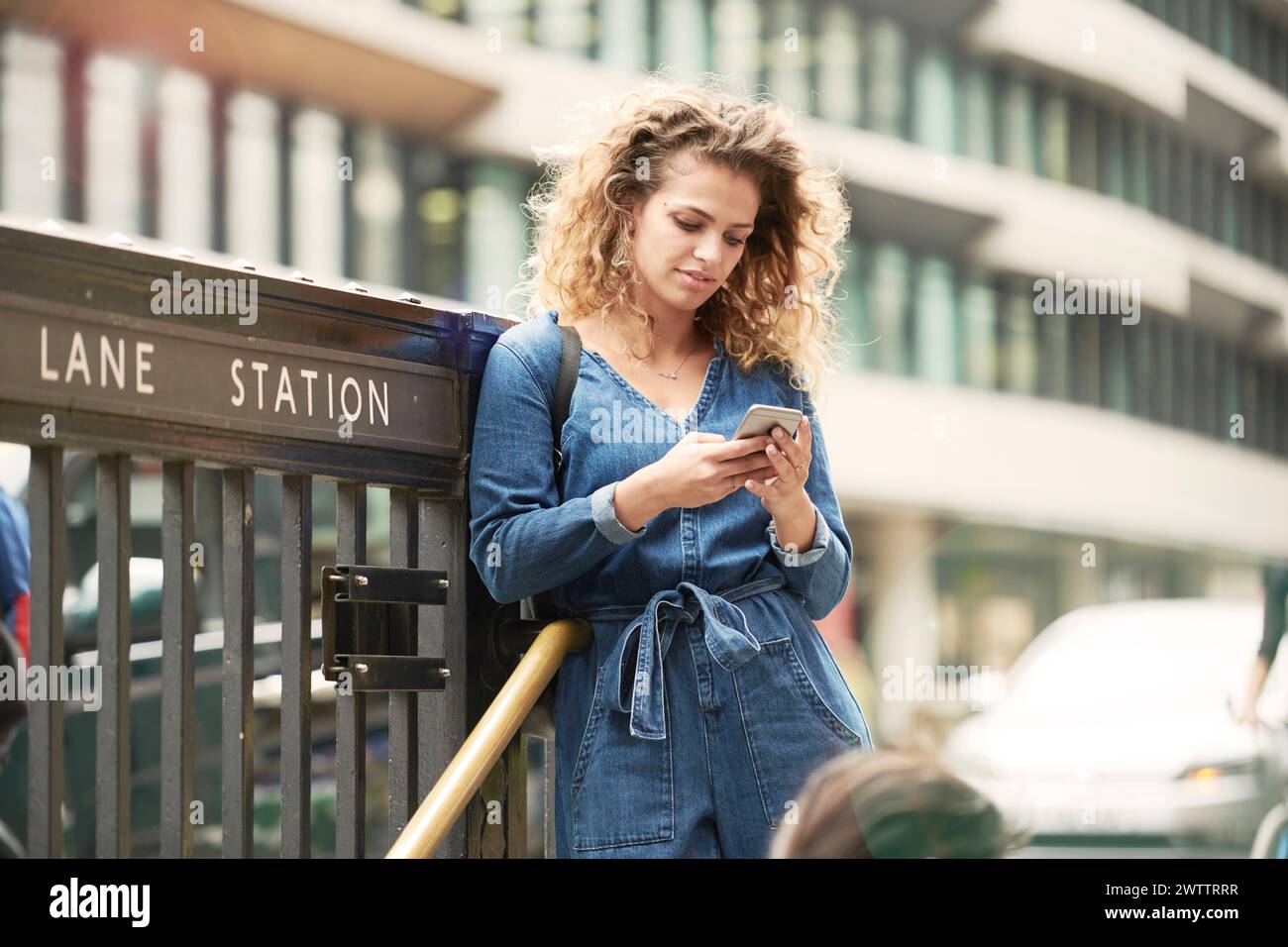 Woman using smartphone at a train station Stock Photo
