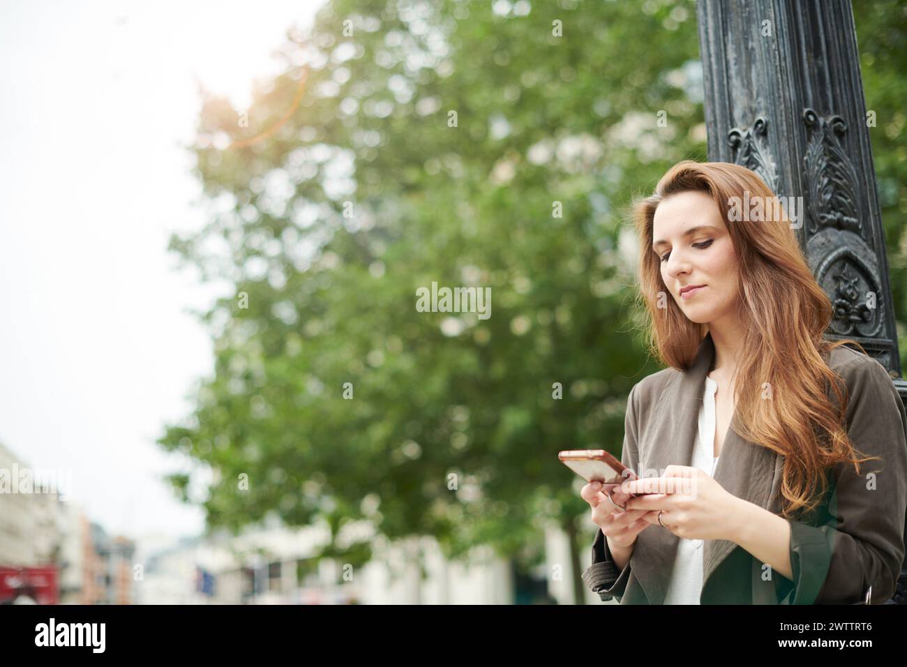 Woman using smartphone on city street Stock Photo
