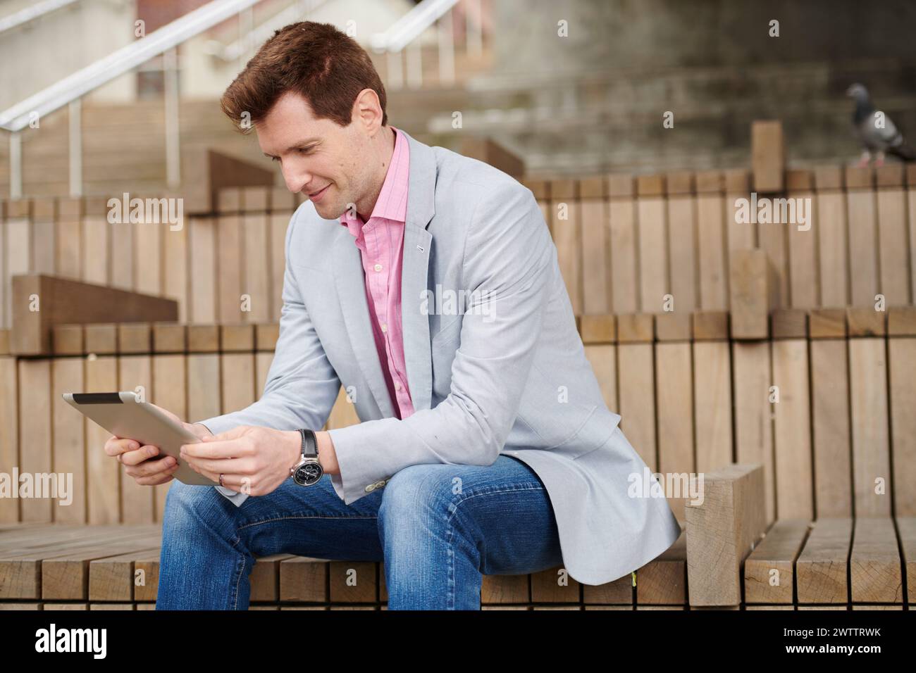 Man sitting on steps using a tablet Stock Photo