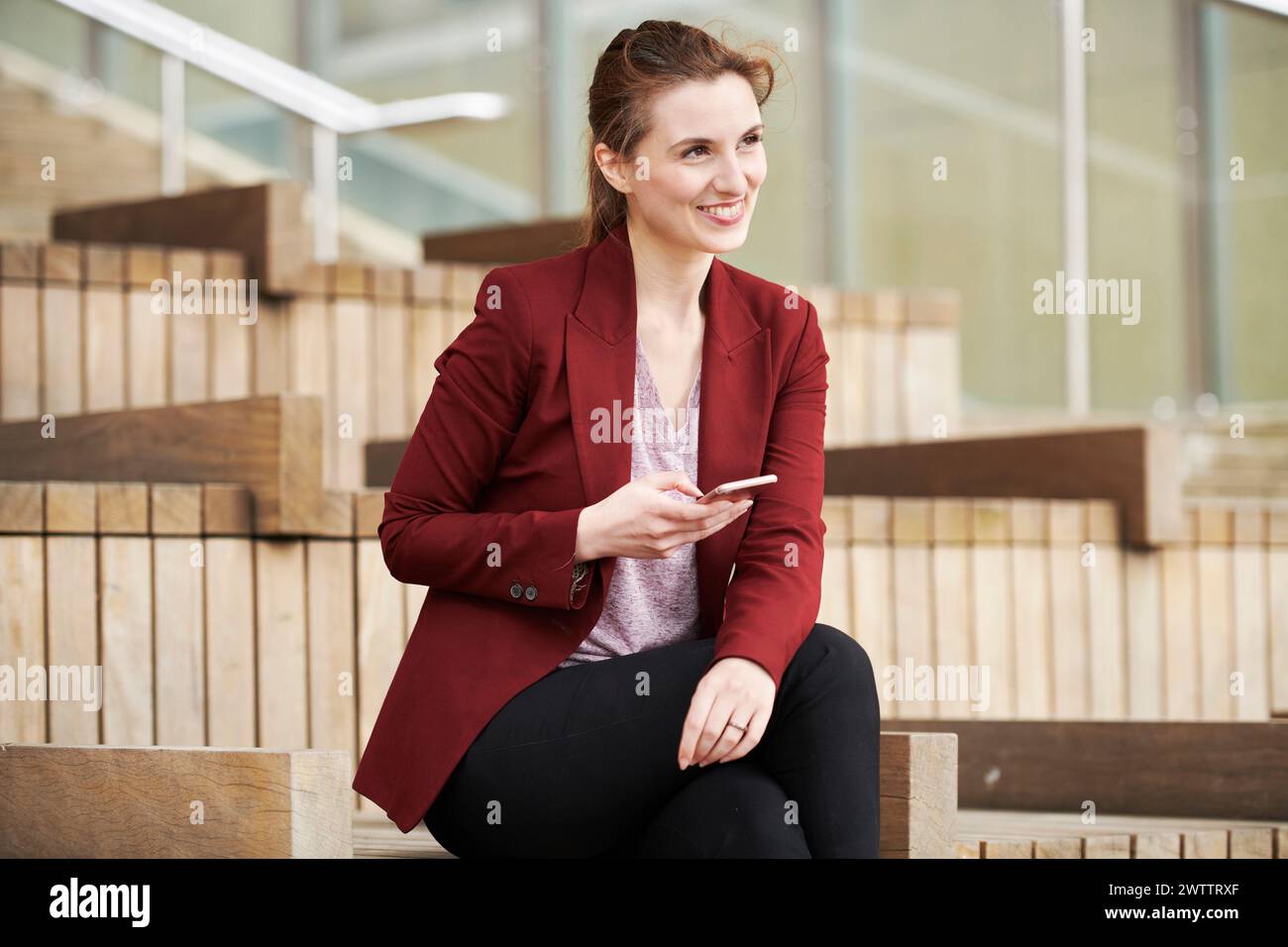 Woman sitting on steps holding a phone Stock Photo