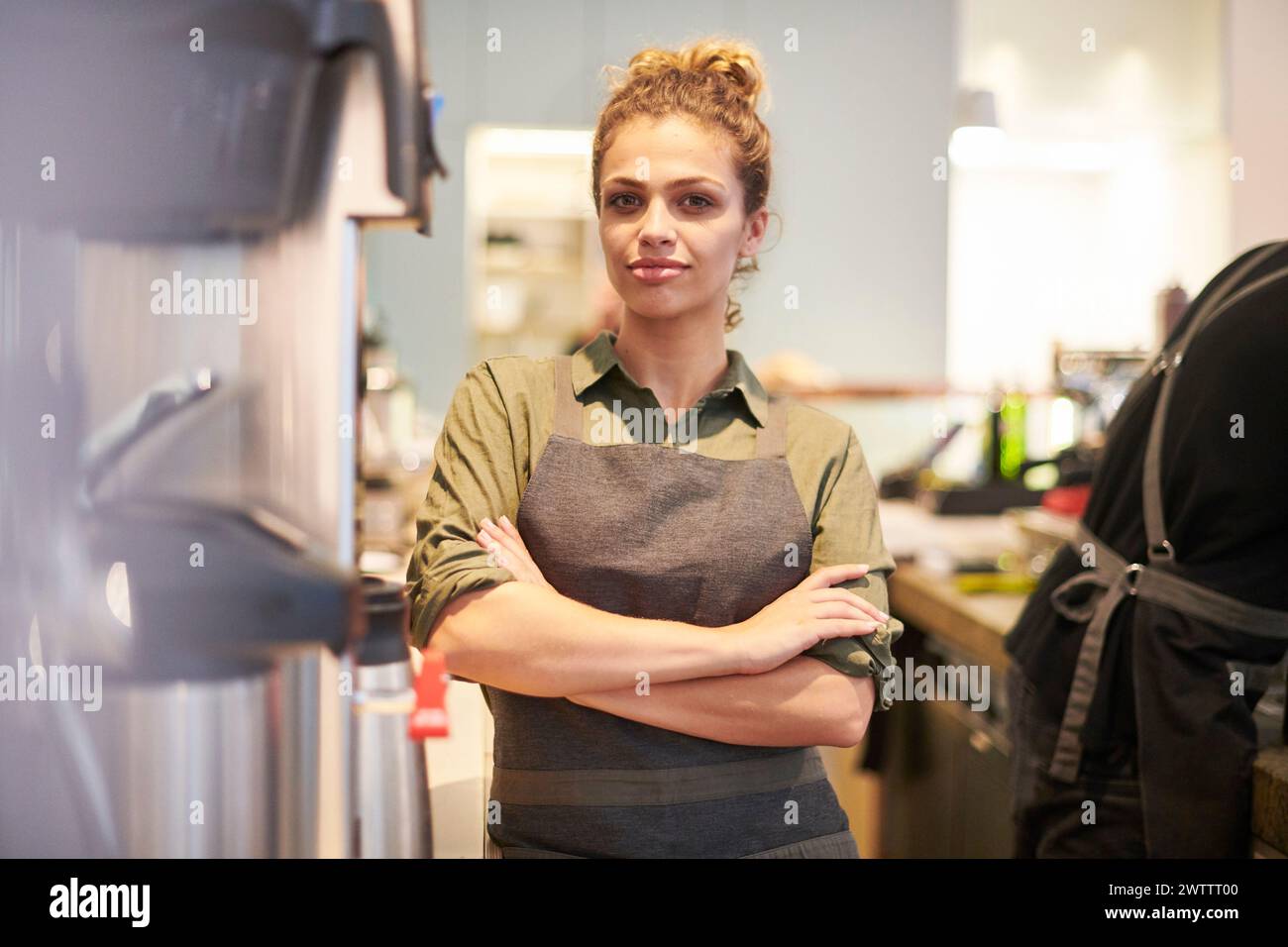 Confident woman in apron standing in a kitchen Stock Photo