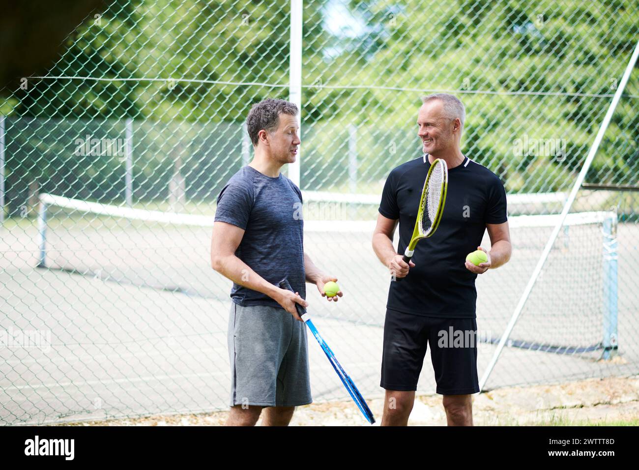 Two men chatting on a tennis court Stock Photo