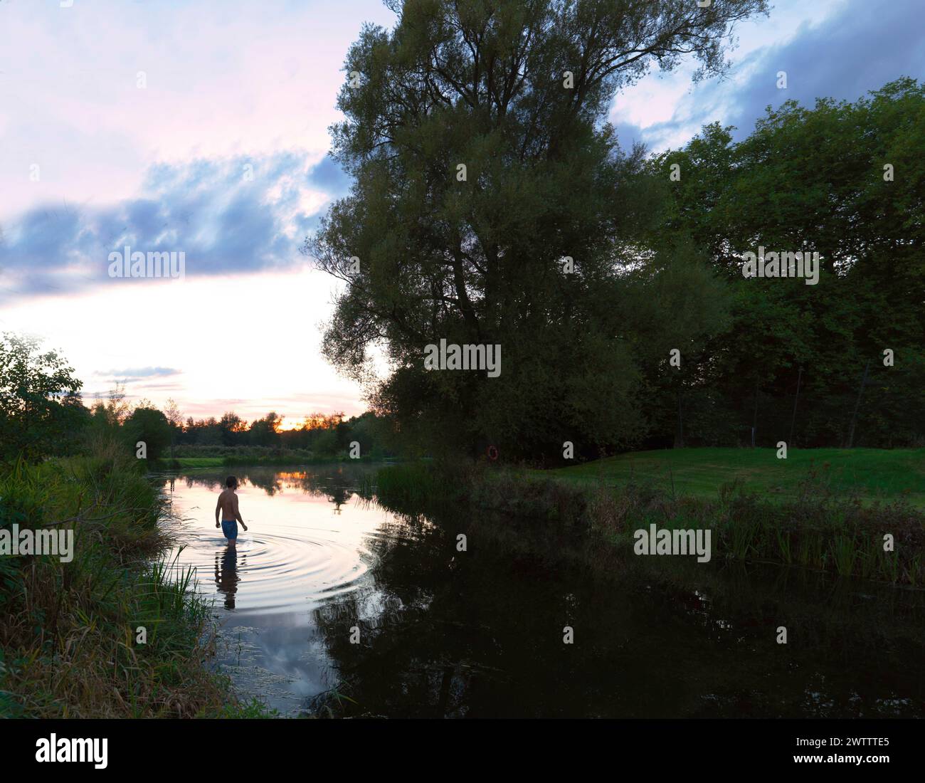 Person standing in water at sunset Stock Photo