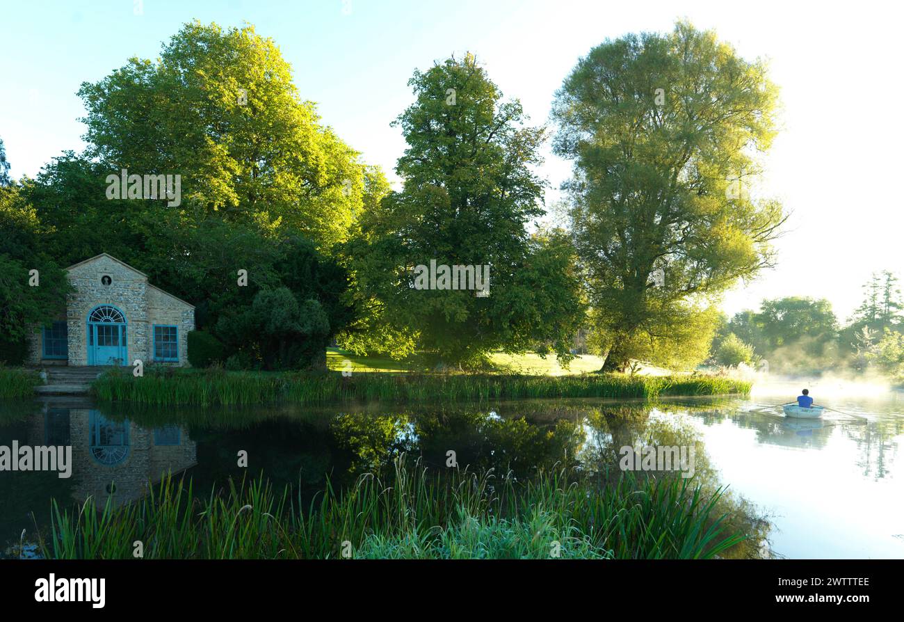 Tranquil lakeside scene with a boater and a stone house Stock Photo