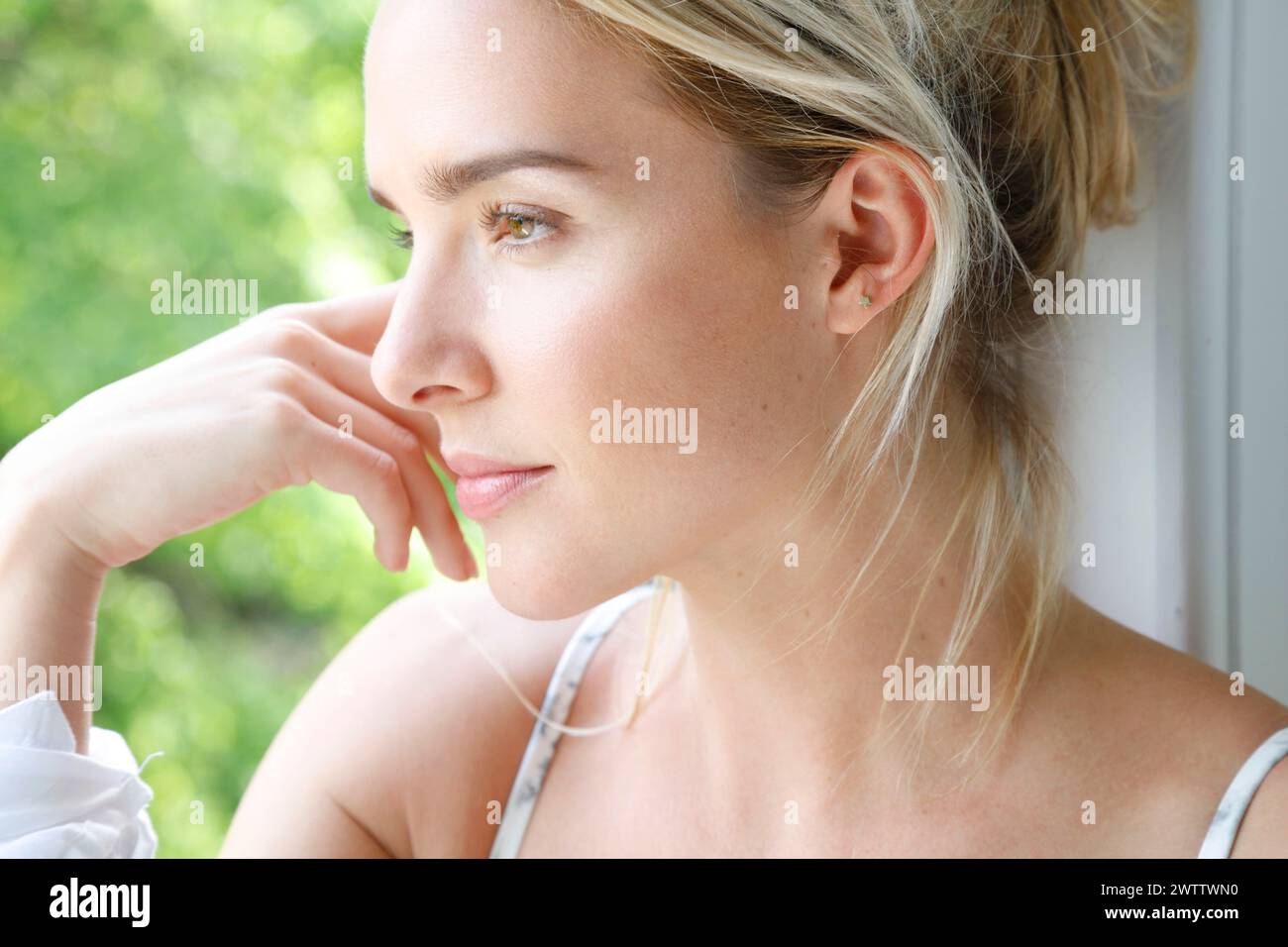Woman gazing out a window in daylight Stock Photo