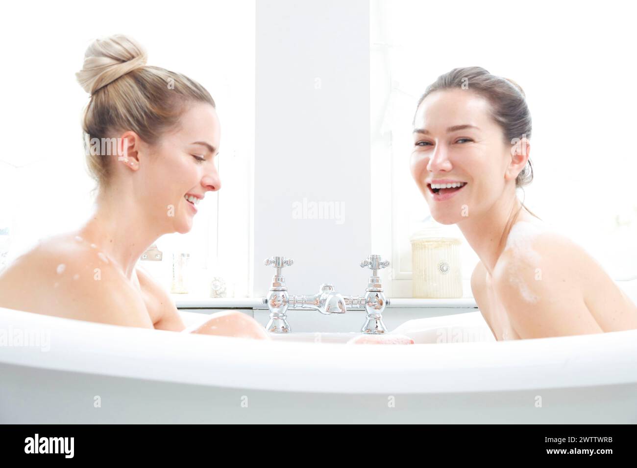 Two women laughing in a bathtub Stock Photo
